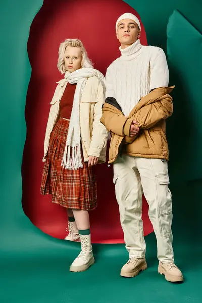 Повна довжина красивого чоловіка в модному зимовому вбранні позує біля жінки на червоному тлі з бірюзовим — стокове фото