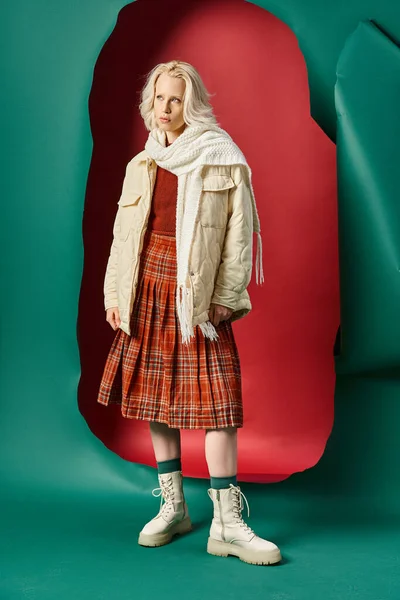 Full length of young blonde woman in winter outfit posing on red with turquoise background — Stock Photo
