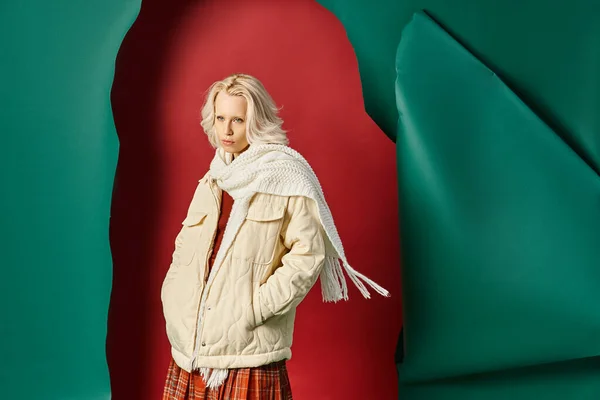 Elegante donna in giacca invernale, sciarpa e gonna a quadri guardando lontano sul rosso con sfondo turchese — Foto stock