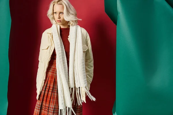 Attractive blonde woman in winter outfit posing in white jacket on red with turquoise backdrop — Stock Photo