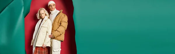 Hombre y mujer con estilo en chaquetas de invierno posando juntos sobre fondo rojo y turquesa desgarrado, pancarta — Stock Photo