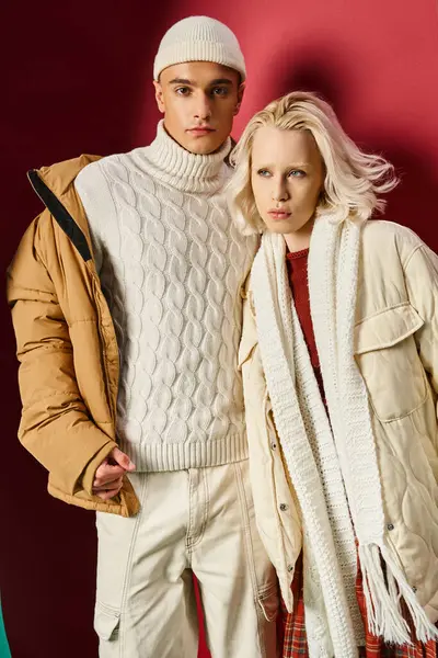 Модный мужчина и женщина в зимней верхней одежде позируют вместе на разорванном бирюзовом и красном фоне — стоковое фото