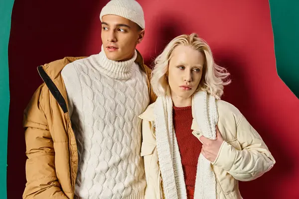 Casal na moda em outerwear inverno posando juntos em turquesa rasgada e fundo vermelho — Fotografia de Stock