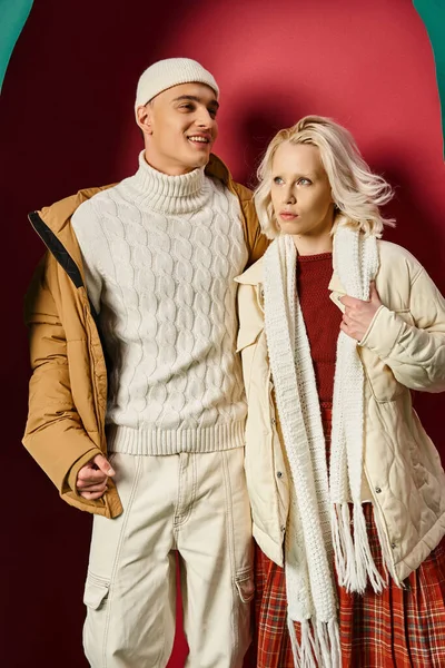 Счастливый мужчина и модная женщина в зимней верхней одежде позировать на разорванных бирюзовый и красный фон — стоковое фото