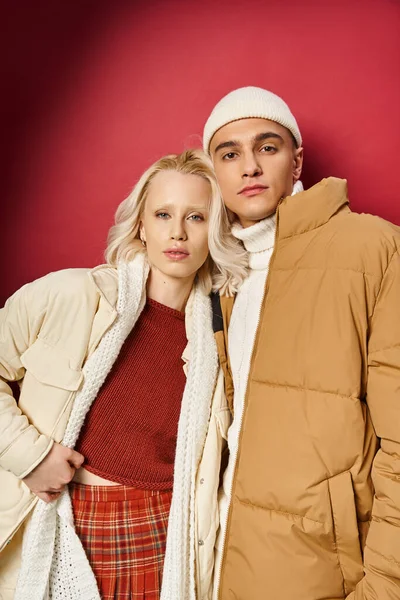 Uomo e donna alla moda in capispalla inverno alla moda in posa insieme su sfondo rosso, moda inverno — Foto stock