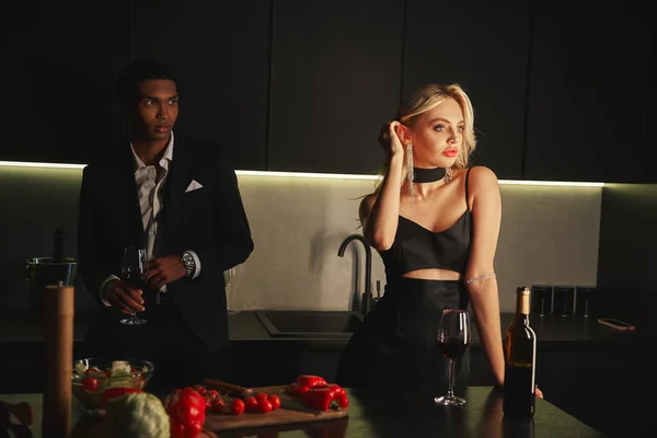 Handsome african american man in suit looking at his beautiful young girlfriend while in kitchen — Stock Photo