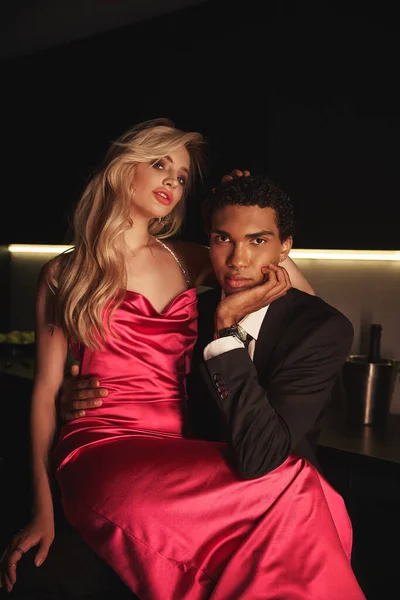 Attraktives multikulturelles Paar in eleganten Outfits mit Accessoires, die vor der Kamera sitzen — Stock Photo