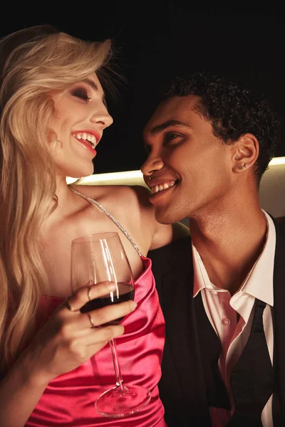 Joyeux jeune couple multiracial en tenue de soirée élégante souriant joyeusement et posant ensemble — Photo de stock