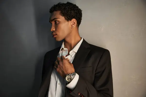 Buen aspecto joven afroamericano hombre con accesorios en traje negro posando y mirando hacia otro lado - foto de stock