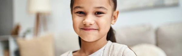 Portrait of happy elementary age girl with brunette hair smiling in modern apartment, banner — Stock Photo