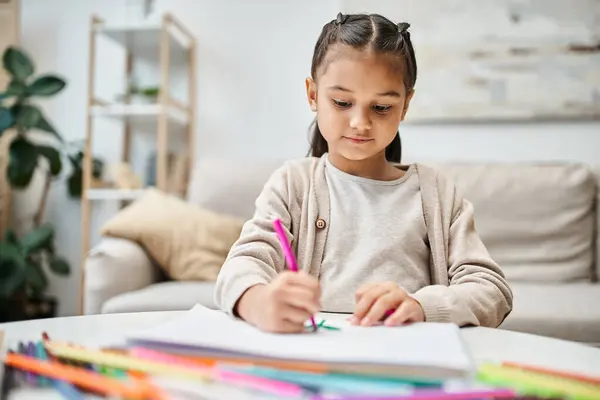 Retrato de niña linda edad elemental dibujo con lápiz de color sobre papel en apartamento moderno - foto de stock