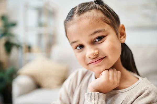 Portrait of smiling elementary age girl with brunette hair looking at camera in modern apartment — Stock Photo