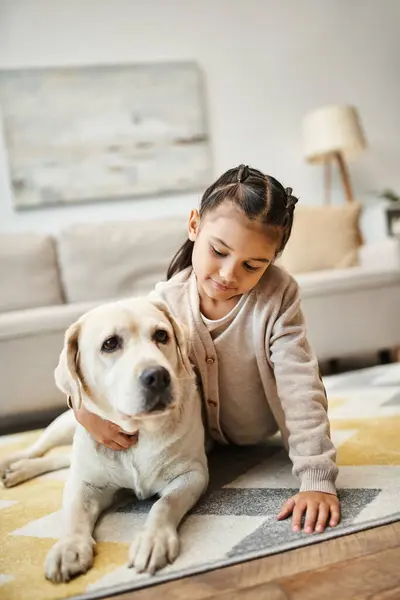 Cute elementary age child in casual attire lying on carpet with labrador in modern living room — Stock Photo