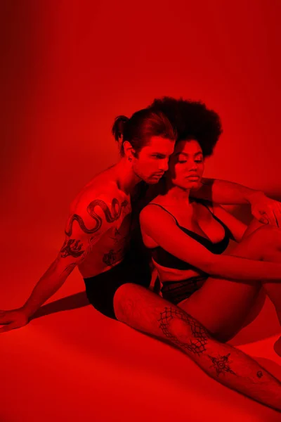 Bonito homem com tatuagens posando alluringly com seu bonito afro americano namorada, sexy casal — Fotografia de Stock
