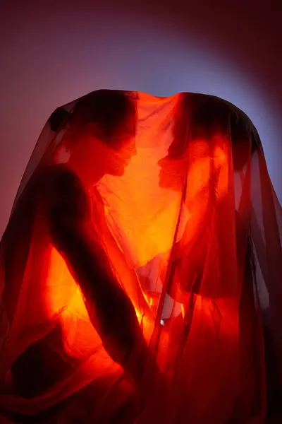 Pareja multirracial cubierta con sábanas rodeadas de luz sobre fondo gris, unión - foto de stock