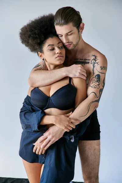 Привлекательный молодой многорасовый парень и девушка в нижнем белье обнимаются тепло, вместе — стоковое фото