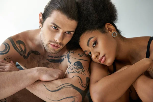 Séduisant jeune couple multiracial en sous-vêtements assis près l'un de l'autre sur le lit, ensemble — Photo de stock