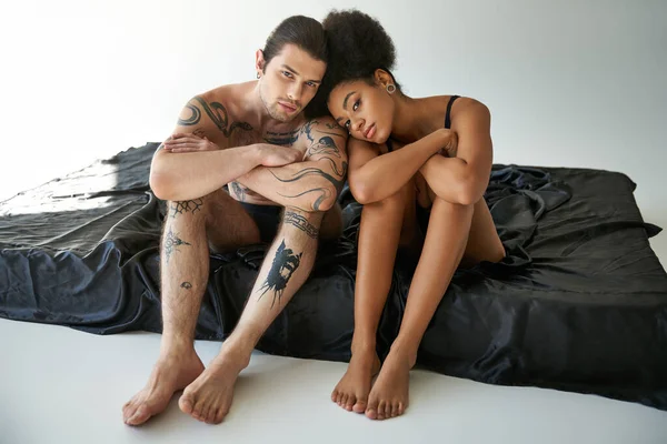 Amour jeune couple multiracial en sous-vêtements assis près de l'autre sur le lit, ensemble — Photo de stock