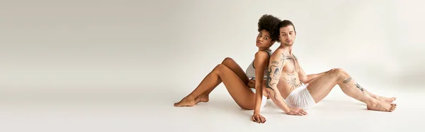 Gut aussehende vielfältige Freund und Freundin Rücken an Rücken auf dem Boden sitzen, sexy Paar, Banner — Stockfoto