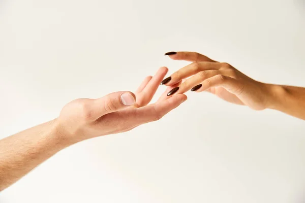 Cropped view of interracial young couple touching hands and fingers of each other on ecru background — Stock Photo