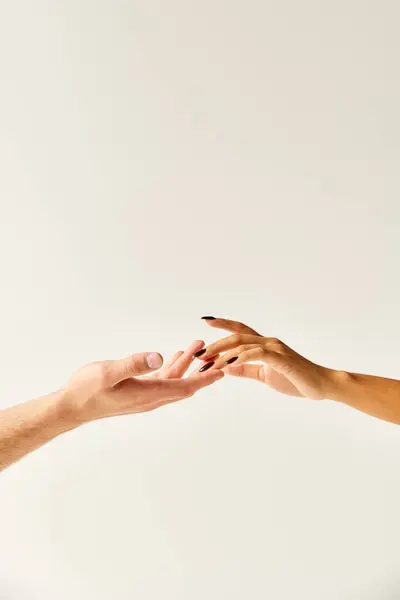 Cropped view of multiracial young couple touching hands and fingers of each other on ecru background — Stock Photo