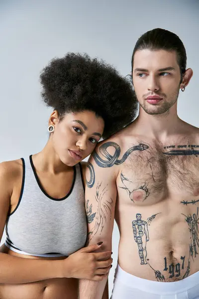Giovane bella coppia multiculturale in biancheria intima posa amorevolmente insieme su sfondo grigio — Foto stock