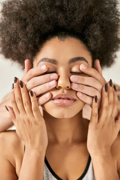Atractiva mujer afroamericana posando con las manos de su joven novio en su cara, pareja - foto de stock