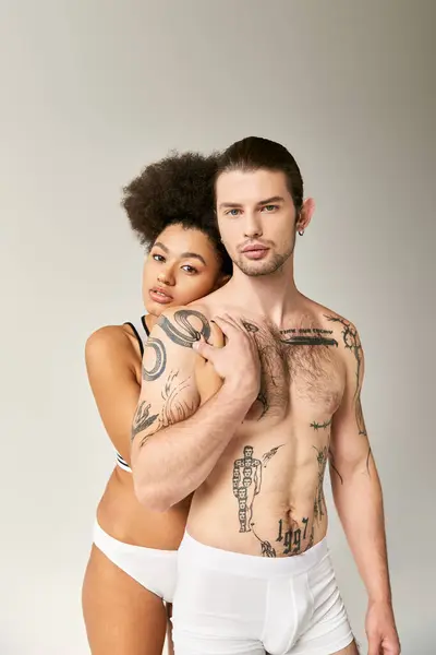 Joven atractiva africana americana mujer abrazando su tatuado novio por detrás, sexy pareja - foto de stock