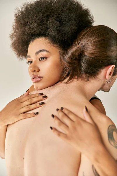 Atractiva joven afroamericana mujer y su novio tatuado abrazándose calurosamente, sexy pareja - foto de stock