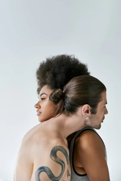 Красивая молодая африканская американская женщина и ее татуированный бойфренд обнимаются теплой сексуальной парой — стоковое фото