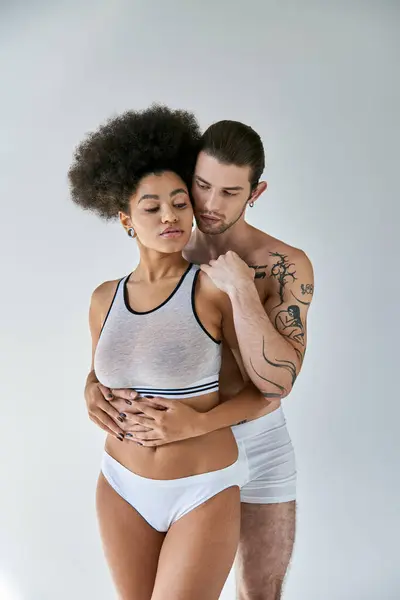 Bonita joven afroamericana mujer y su tatuado novio abrazando calurosamente, sexy pareja - foto de stock