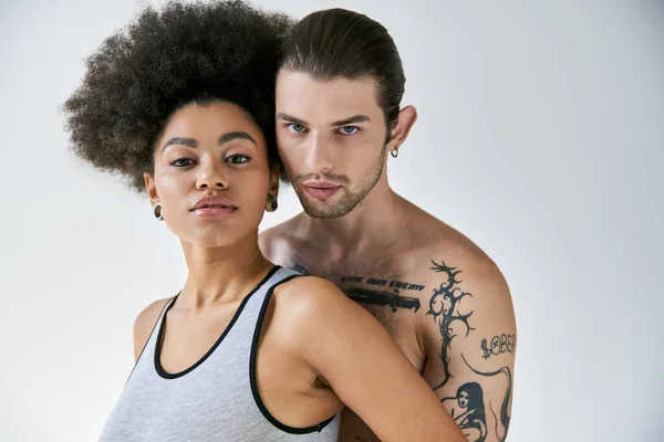 Привлекательная молодая африканская американка и ее татуированный бойфренд обнимаются с любовью, сексуальная пара — стоковое фото