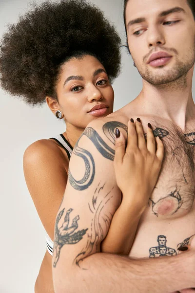 Cuidado de la joven afroamericana mujer abrazando a su novio guapo por detrás, sexy pareja - foto de stock