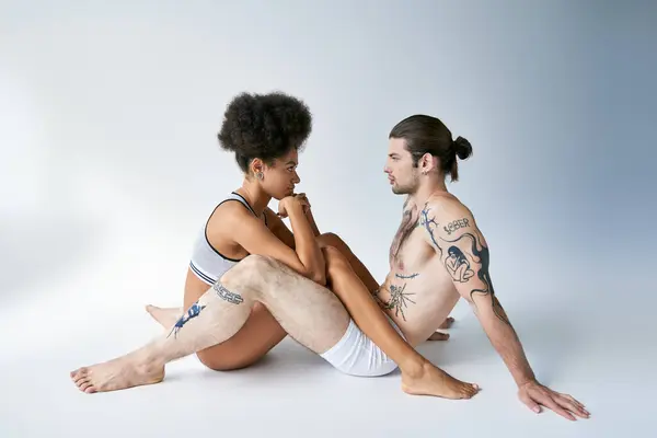 Приваблива молода багатокультурна пара в сексуальній комбінованій білизні, сидячи на підлозі, — стокове фото