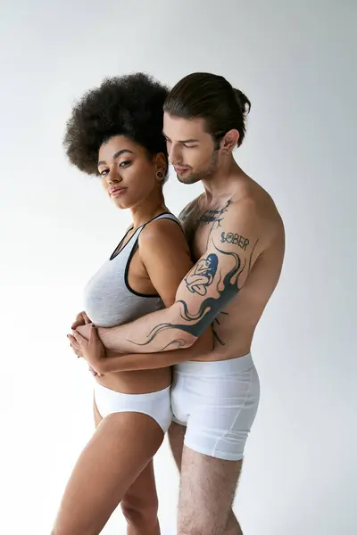 Young tattooed man hugging his beautiful african american girlfriend from behind, sexy couple — Stock Photo
