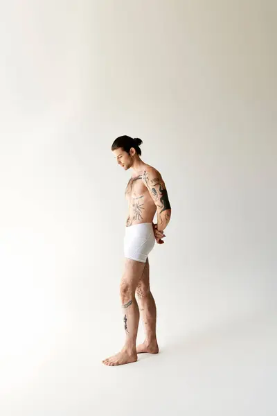 Сексуальний хороший чоловік з хвіст і круті татуювання в нижній білизні позує на екологічному фоні — стокове фото