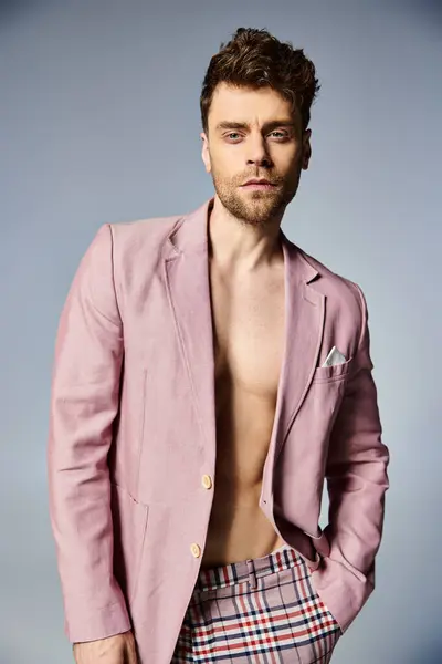 Handsome stylish man in unbuttoned vibrant pink suit posing on gray backdrop, fashion concept — Stock Photo