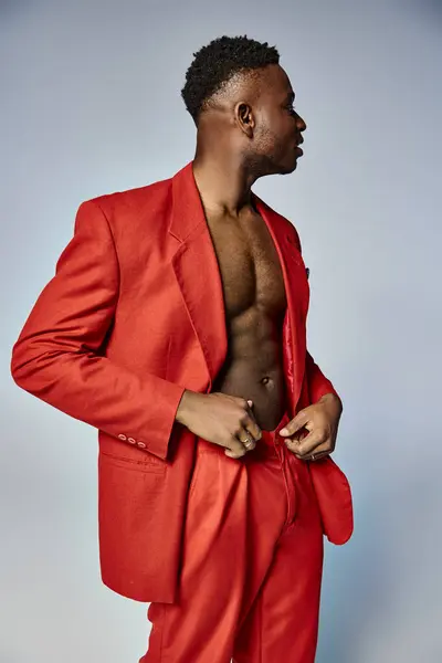 Appealing african american man in vibrant red attire posing on gray backdrop, fashion concept — Stock Photo