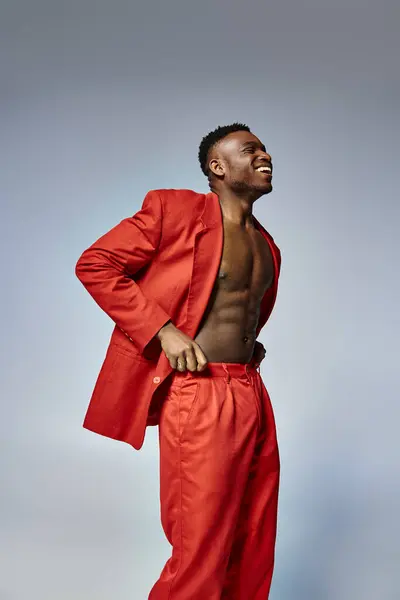 Modelo masculino afroamericano joven con estilo elegante vibrante posando sobre fondo gris, concepto de moda - foto de stock