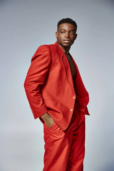 Bell'uomo afro-americano in vivace abbigliamento rosso in posa su sfondo grigio, concetto di moda — Foto stock