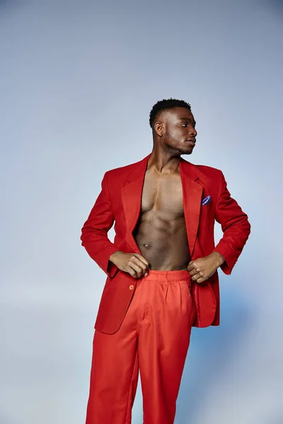 Bel homme élégant afro-américain en costume rouge posant sur fond gris, concept de mode — Photo de stock