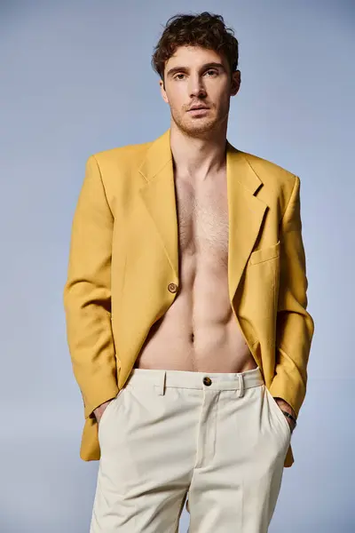 Jovem bonito na jaqueta amarela elegante posando atrativamente no fundo cinza, conceito de moda — Fotografia de Stock