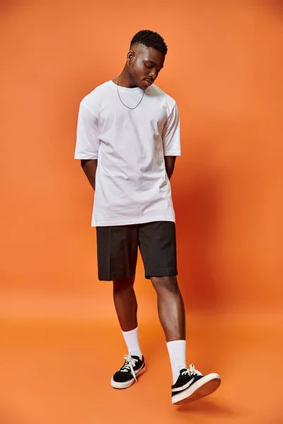 Attrayant jeune homme afro-américain en tenue décontractée de rue sur fond orange, concept de mode — Photo de stock
