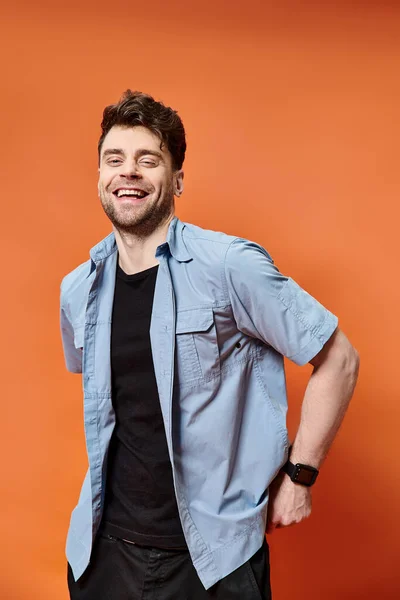 Happy attractive man in casual outfit on orange backdrop looking at camera, fashion concept — Stock Photo