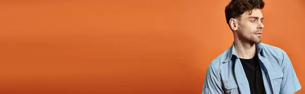 Attrayant homme en tenue décontractée tendance sur fond orange regardant la caméra, concept de mode — Photo de stock