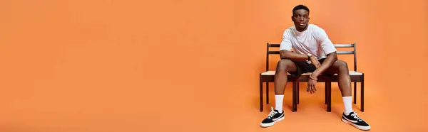 Schöner junger afrikanisch-amerikanischer mann im urbanen outfit sitzt auf bank, modekonzept, banner — Stockfoto