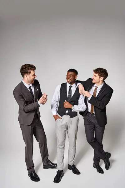 Alegres jóvenes amigos multiculturales en trajes casuales de negocios sonriendo y divirtiéndose - foto de stock