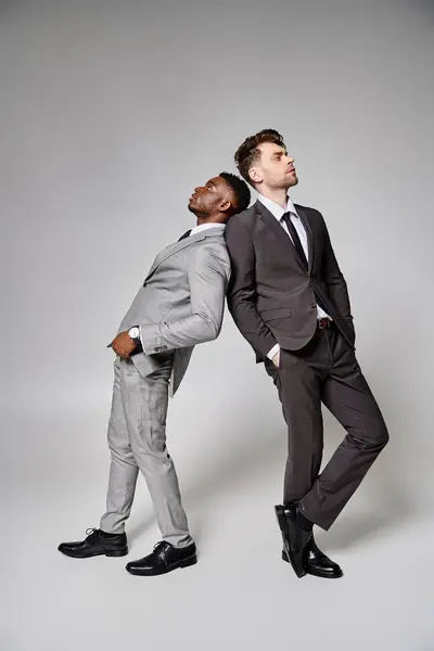 Two attractive stylish multicultural male models in business smart attires posing on gray backdrop — Stock Photo