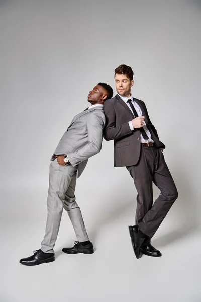 Deux attrayants modèles masculins multiculturels élégants en affaires vêtements intelligents posant sur fond gris — Photo de stock
