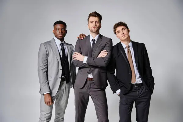 Alluring young multicultural male models in business casual attires posing on gray backdrop — Stock Photo